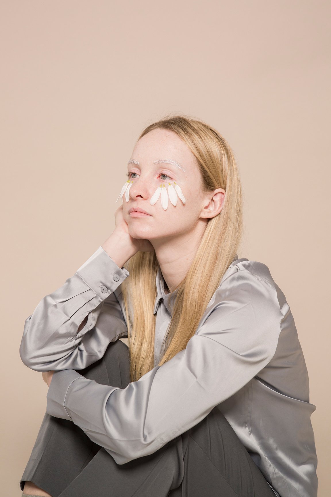 Lady with white flower petals on face in studio